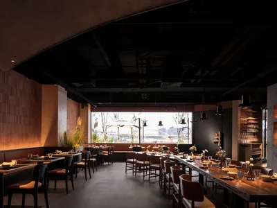 現代餐廳室內空間，配有木質餐桌、混凝土牆面，以及工業風格燈具。