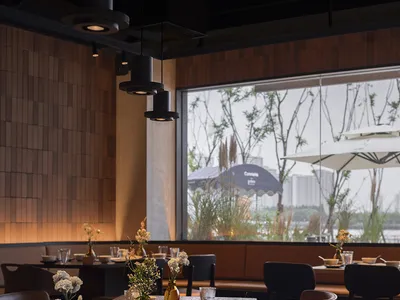 A modern industrial restaurant interior with wood tables, leather seating, and metal accents.