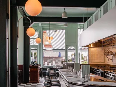 Restaurant bar interior with metallic stools, checkered flooring, and industrial design elements.