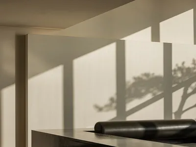 Modern minimalist restaurant bar with concrete surfaces and stools.