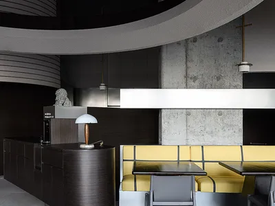 A modern restaurant interior featuring dark wood accents and concrete walls.