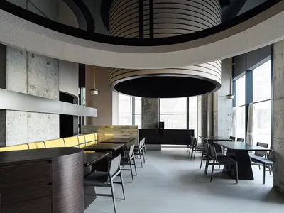 Modern restaurant interior with concrete walls, wooden furniture, and large windows.