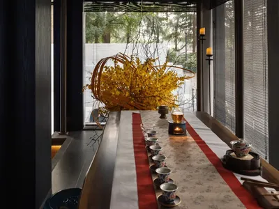 A modern restaurant interior features a wooden table adorned with candles, creating a cozy and inviting atmosphere.