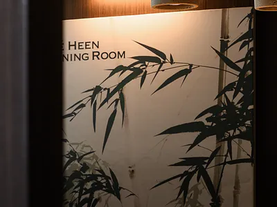 圓形木桌中央擺放陶瓷花瓶，背景為竹子植物海報。