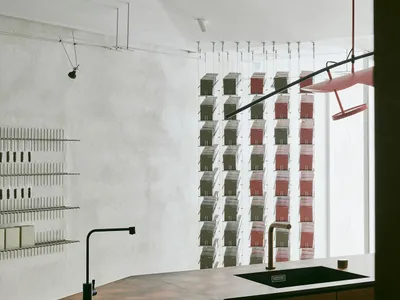 A modern kitchen with a metallic countertop, industrial style lighting, and a row of suspended shelves.