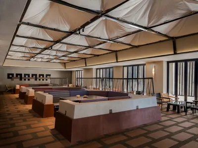 Hotel lobby featuring modern, minimalist design with fabric-covered concrete seating and carpeted flooring.