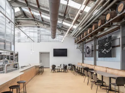 Industrial-style restaurant interior featuring concrete, metal, and glass materials.