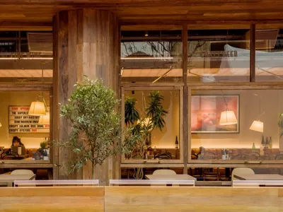 A rustic, industrial-themed restaurant interior with wooden accents and greenery.