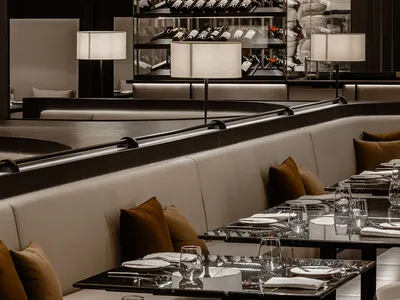 Modern restaurant interior with glass shelves, steel accents, and leather seating