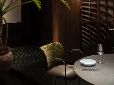 Modern restaurant interior featuring walnut paneling and industrial-style lighting.