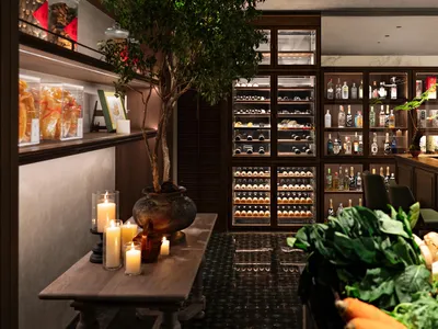 A photograph of a modern bar interior featuring a counter with candles and a tree.