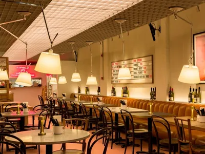 An interior view of a modern cafe with leather seating, round tables, and hanging lamps.