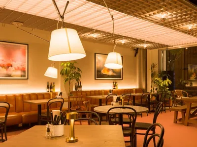 Modern cafe interior featuring wood tables, leather seating, and metal chairs.