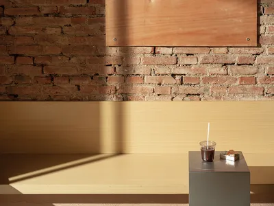 A coffee shop interior with a red brick wall, a wooden sign displaying 'Mirror Coffee', and a cup of coffee on a small table.