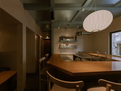 Industrial-style restaurant bar with wooden furniture and a variety of alcohol bottles displayed on shelves.