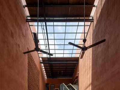 An industrial-style restaurant interior featuring wooden tables and terracotta walls with glass ceiling panels.