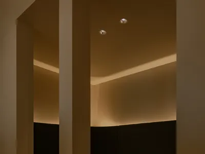 A modern booth area in a restaurant or cafe with wooden tables and cushions on a concrete floor.
