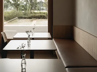 A minimalist restaurant interior with modern elements and a view of greenery outside.