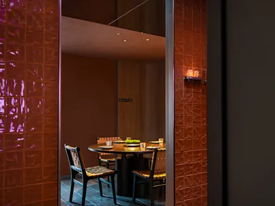 A modern restaurant interior with wooden tables, chairs, and walls.