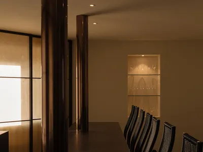 A sleek, modern restaurant bar featuring wooden columns, illuminated by recessed lighting.