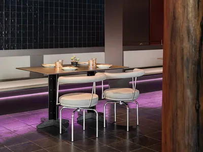 Modern restaurant interior with black tiles, metallic furniture, and purple lighting