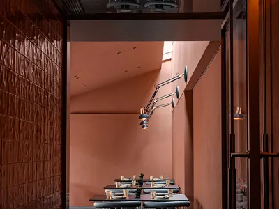 A modern restaurant dining room with metallic textured walls and black, industrial-style chairs.