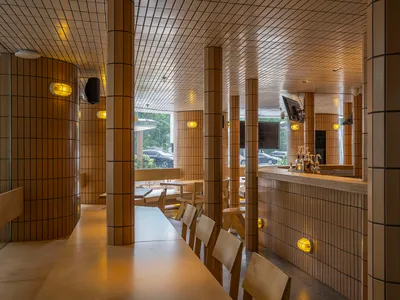 Interior view of a modern restaurant featuring tiled walls and wooden furniture.