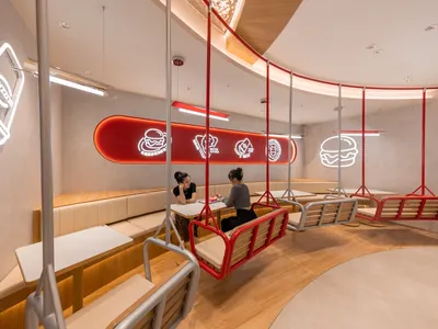 People sitting at a modern cafe with metal chairs and neon signs.