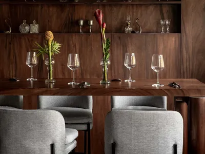 A modern industrial-style restaurant interior with wooden walls, shelves, and a table, and fabric-covered seating.