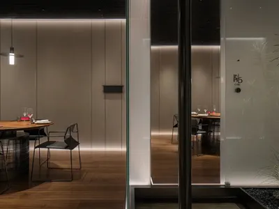 Modern minimalist dining room with metallic furniture and glass elements.