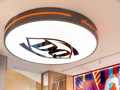 A modern restaurant interior with colorful walls, round light fixture, and contemporary seating.