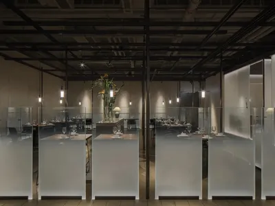 A sleek modern restaurant interior with glass walls and ceiling