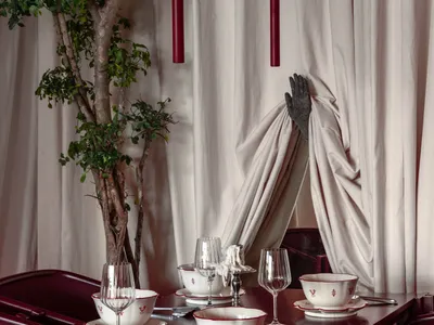 Modern restaurant interior featuring wooden furniture, glassware, and green plant.