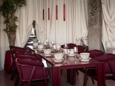 A restaurant interior featuring modern design elements such as curtains and glass tables.