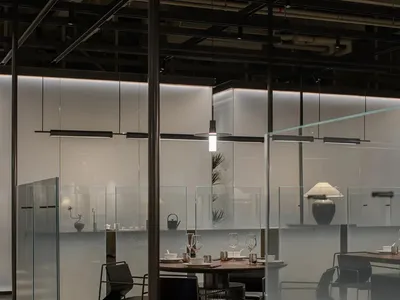 Modern restaurant interior with frosted glass panel walls and industrial-style furnishings.