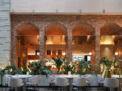 A modern industrial restaurant with brick walls, metal accents, concrete finishes, and lush greenery.