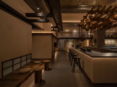 Interior of an industrial-style restaurant with wooden elements and bar seating.