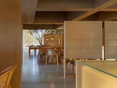 Interior of a minimalist restaurant featuring concrete and woven materials.