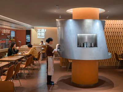 極簡餐廳室內空間，搭配金屬柱與軟木牆，展現俐落設計與實用功能。