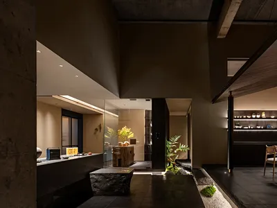 Modern restaurant interior with dark wood and concrete materials.