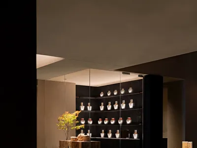 Modern restaurant interior with wooden furniture and shelves showcasing various objects.