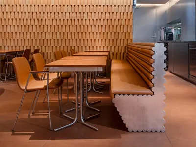 Modern restaurant seating area with chairs and tables made of wood.