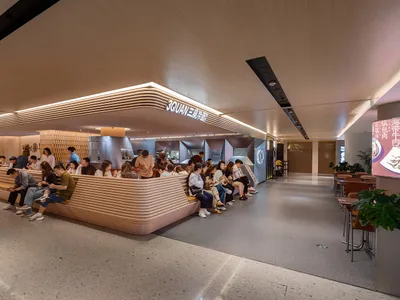 A modern food court with a desk made of wood for customers to eat and sit