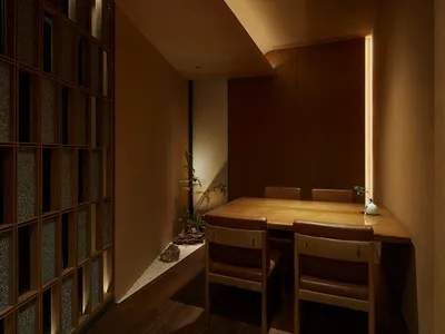A cozy modern restaurant interior with wooden tables, chairs, and a floor-to-ceiling window.