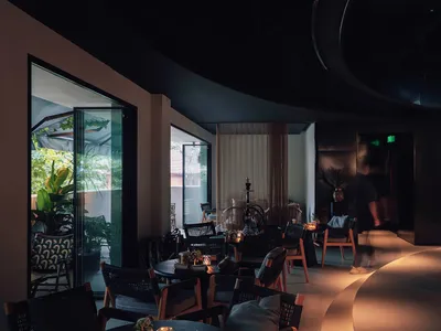 Modern restaurant interior with wooden furniture, glass walls, and metal accents.