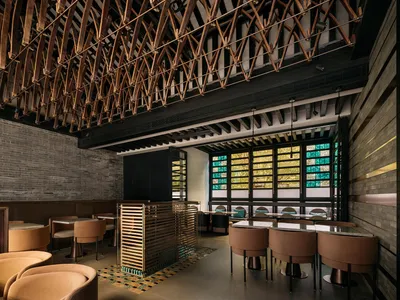 An industrial-themed restaurant interior with wooden structures and concrete walls, featuring glass elements for lighting and