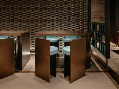 A minimalist restaurant interior featuring concrete walls and wooden furniture.