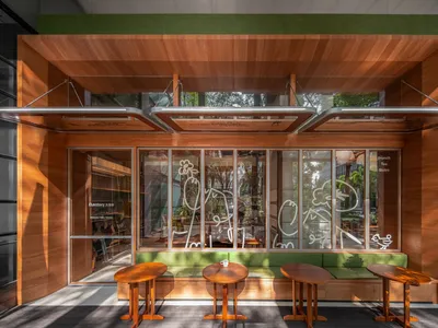 Modern outdoor cafe featuring wooden and glass elements with green accents