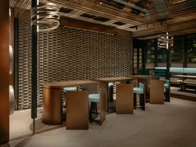 A modern restaurant interior featuring wood laminate tables and chairs.