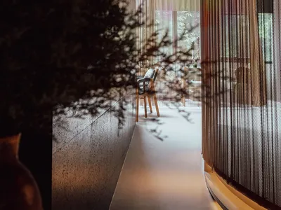 Interior view of a modern restaurant featuring a metal mesh wall and minimalist decor.